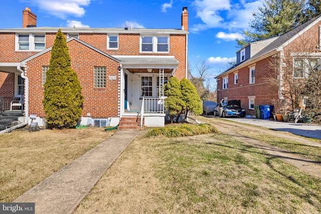 view of front facade with a front yard, a chimney, and brick siding