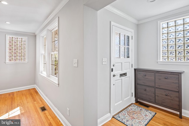 foyer entrance featuring wood-type flooring, visible vents, a wealth of natural light, and ornamental molding