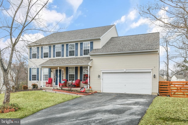 colonial inspired home featuring a garage, covered porch, and a front lawn