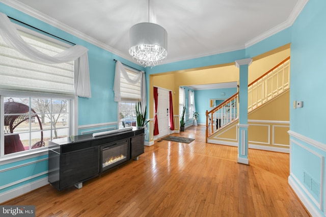 foyer with ornate columns, crown molding, an inviting chandelier, and light hardwood / wood-style flooring