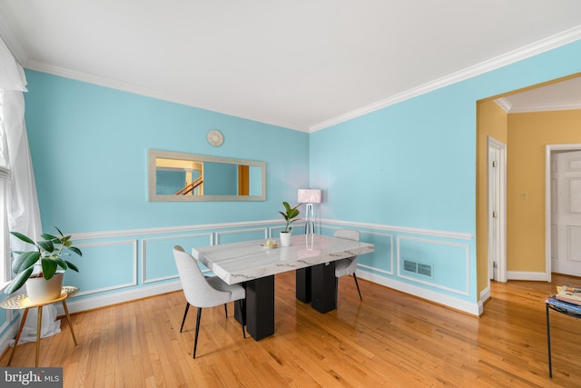 dining room with ornamental molding and light hardwood / wood-style flooring