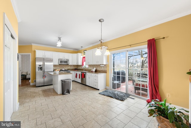 kitchen with white cabinetry, stainless steel appliances, a center island, ornamental molding, and decorative light fixtures