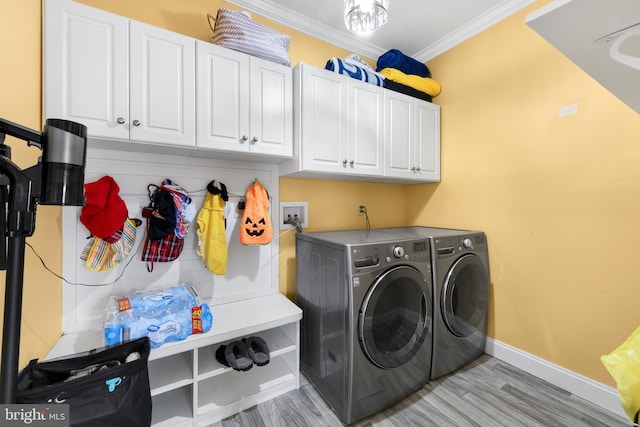 laundry area featuring cabinets, ornamental molding, washer and clothes dryer, and light hardwood / wood-style floors