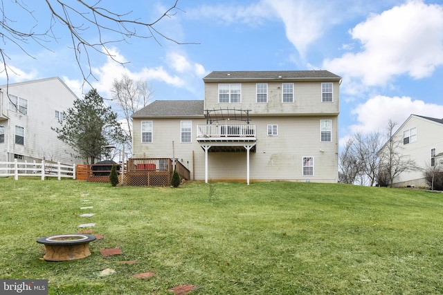 back of house with a yard, a deck, and an outdoor fire pit