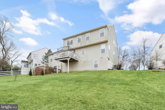 rear view of property featuring a wooden deck and a lawn