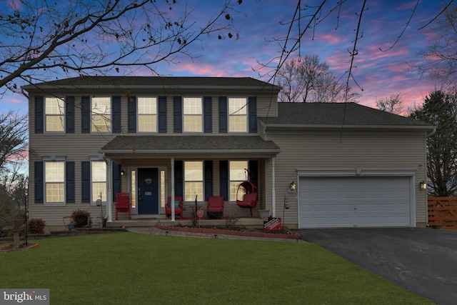 view of front facade featuring a garage, a yard, and covered porch