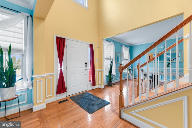 entryway featuring crown molding, wood-type flooring, and a high ceiling