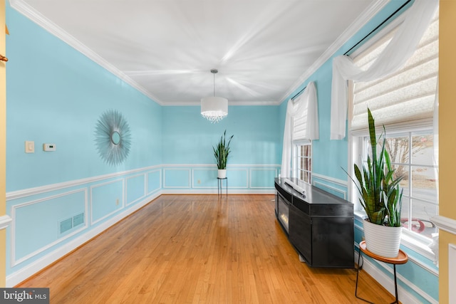 living area featuring ornamental molding, a notable chandelier, and light wood-type flooring