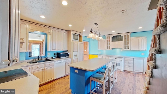 kitchen with a breakfast bar, pendant lighting, a center island, white appliances, and light wood-type flooring