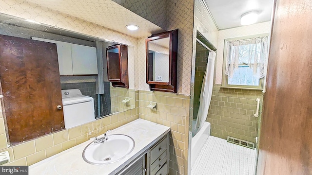 bathroom with shower / tub combo with curtain, vanity, washer / clothes dryer, and tile walls