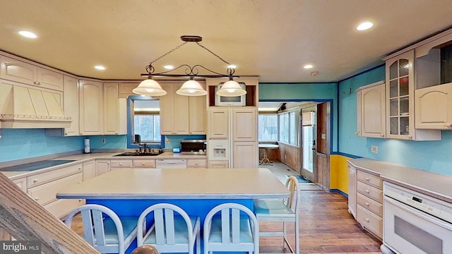 kitchen featuring white appliances, a kitchen bar, a center island, and custom range hood