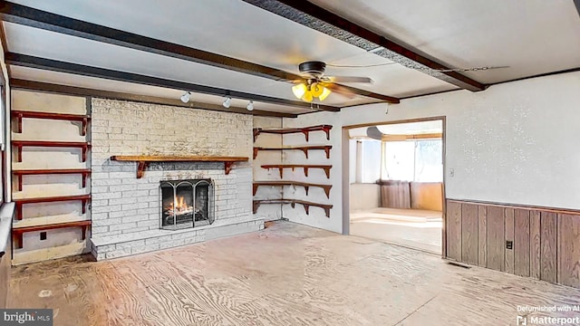 unfurnished living room with beamed ceiling, ceiling fan, wooden walls, and a fireplace