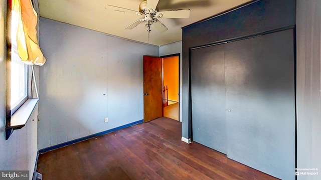 unfurnished bedroom with dark hardwood / wood-style flooring, a closet, and ceiling fan