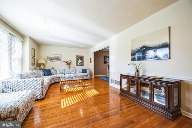 living area with wood-type flooring, visible vents, and baseboards