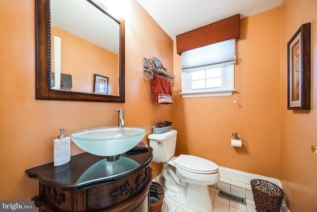 bathroom featuring visible vents, toilet, a sink, tile patterned flooring, and baseboards