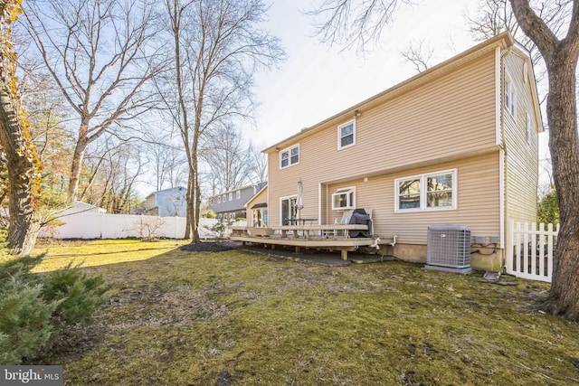 back of property with fence, a deck, central AC, and a yard