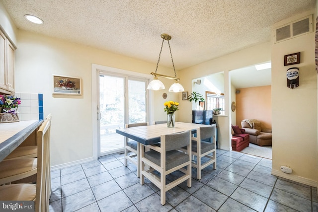 dining space with light tile patterned floors, plenty of natural light, visible vents, and a textured ceiling