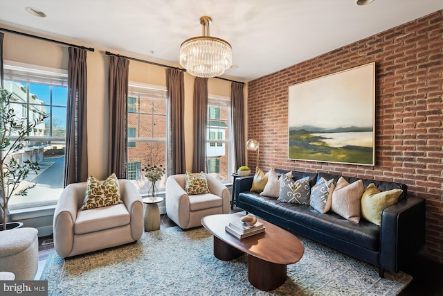 living area featuring hardwood / wood-style floors, a chandelier, a healthy amount of sunlight, and brick wall