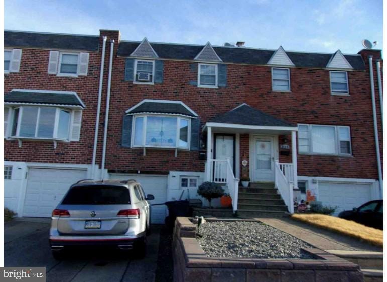 multi unit property featuring driveway, brick siding, and an attached garage