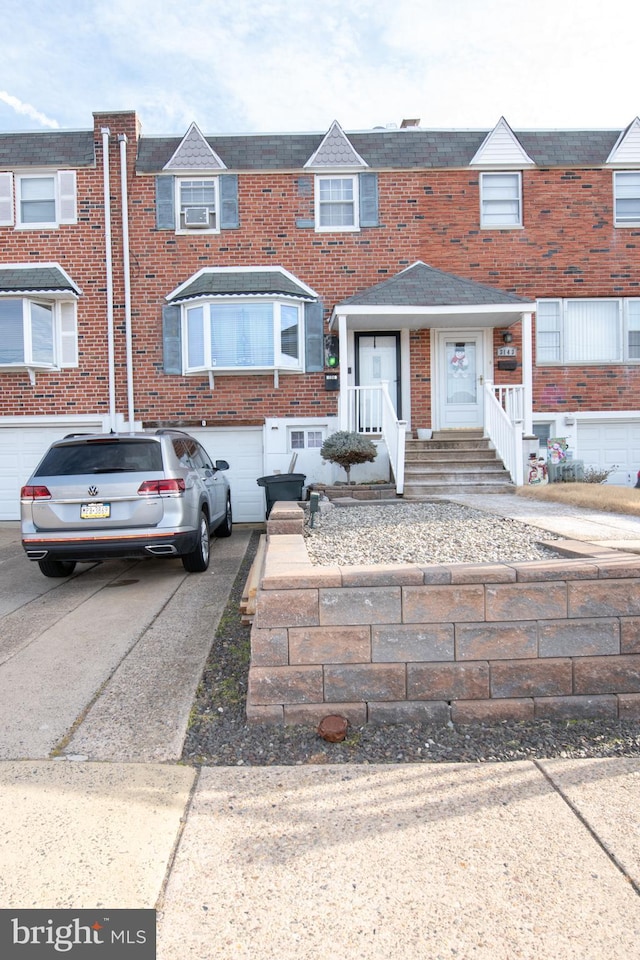 view of property with a garage, concrete driveway, and brick siding