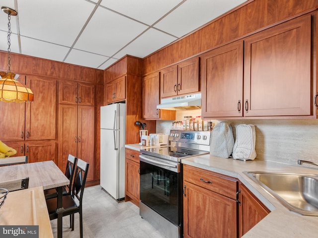 kitchen featuring a paneled ceiling, sink, stainless steel range with electric stovetop, hanging light fixtures, and white fridge