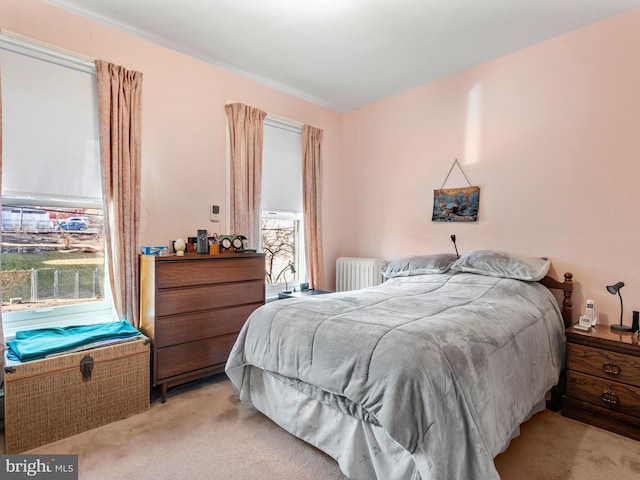 bedroom featuring light carpet and radiator