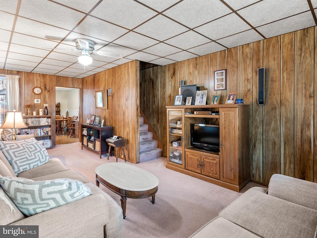 living room with ceiling fan, light carpet, and wood walls