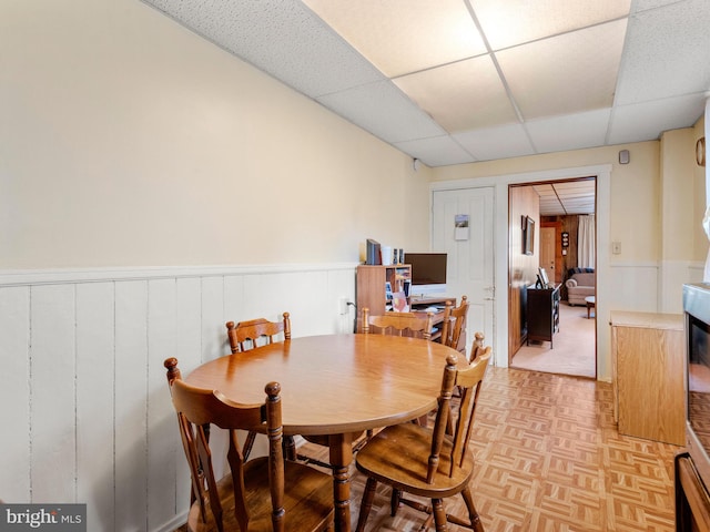 dining room featuring light parquet flooring and a drop ceiling