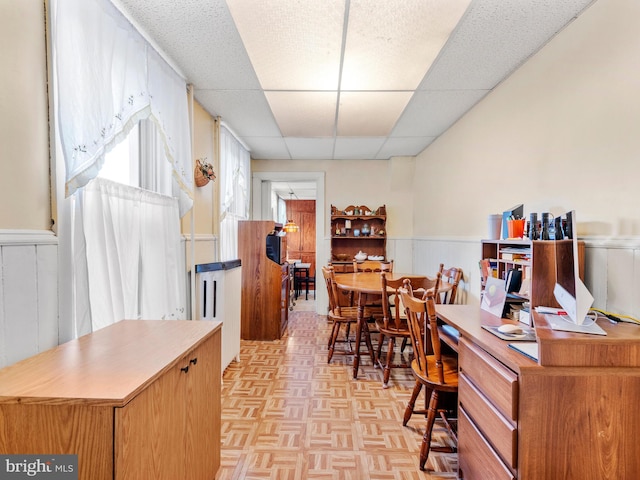 home office with light parquet flooring and a paneled ceiling