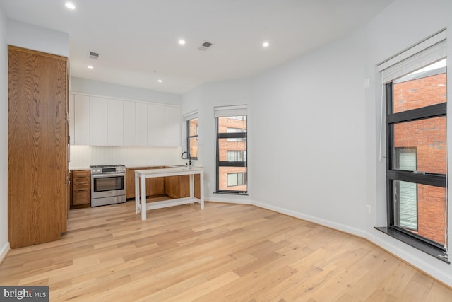 kitchen featuring white cabinetry, light hardwood / wood-style flooring, and stainless steel gas range oven