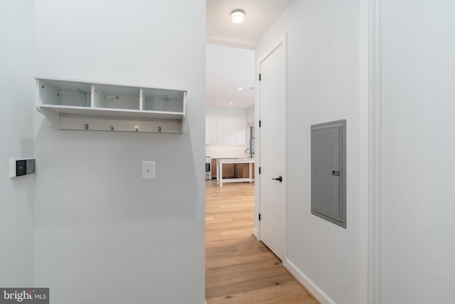 corridor with electric panel and light hardwood / wood-style flooring