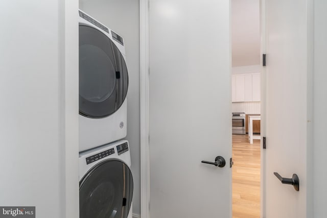 laundry area with hardwood / wood-style flooring and stacked washing maching and dryer