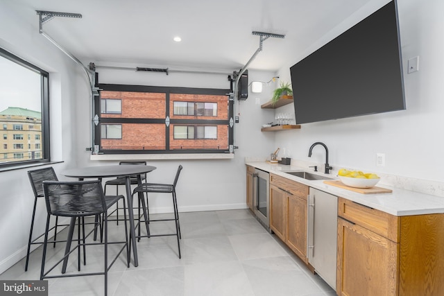 kitchen featuring sink, dishwashing machine, and a kitchen bar