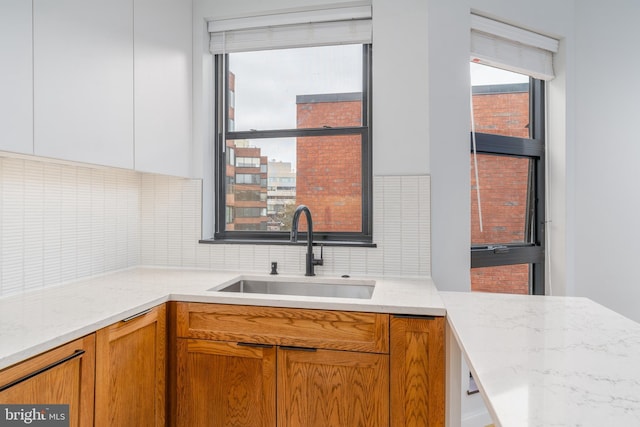 kitchen with tasteful backsplash, sink, and light stone counters