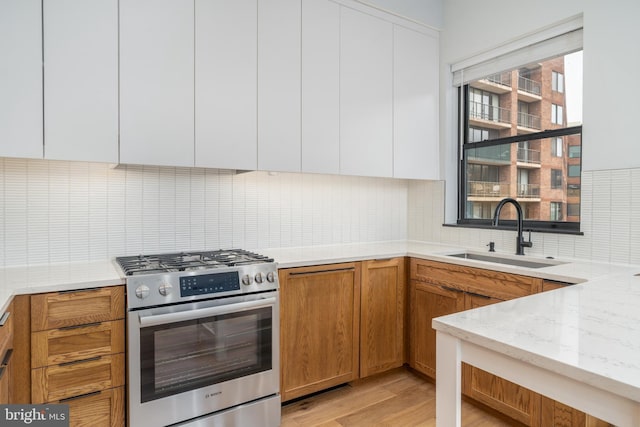 kitchen with sink, stainless steel gas range oven, and white cabinets