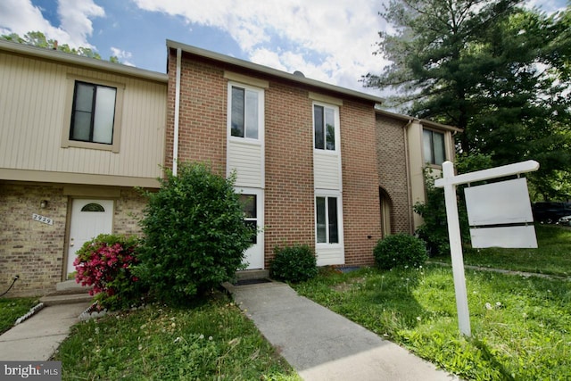 exterior space with brick siding and a front lawn