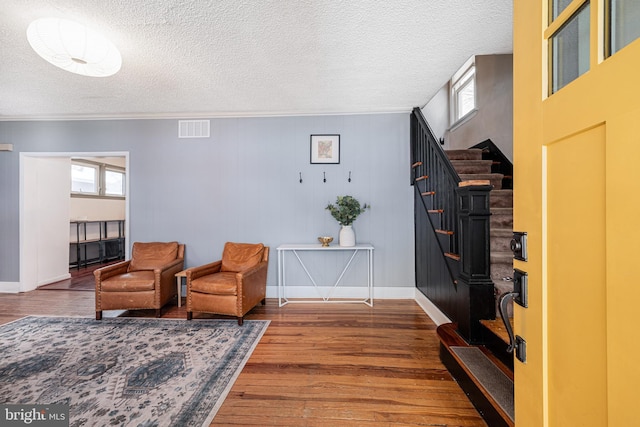 sitting room featuring crown molding, dark wood-type flooring, and a textured ceiling