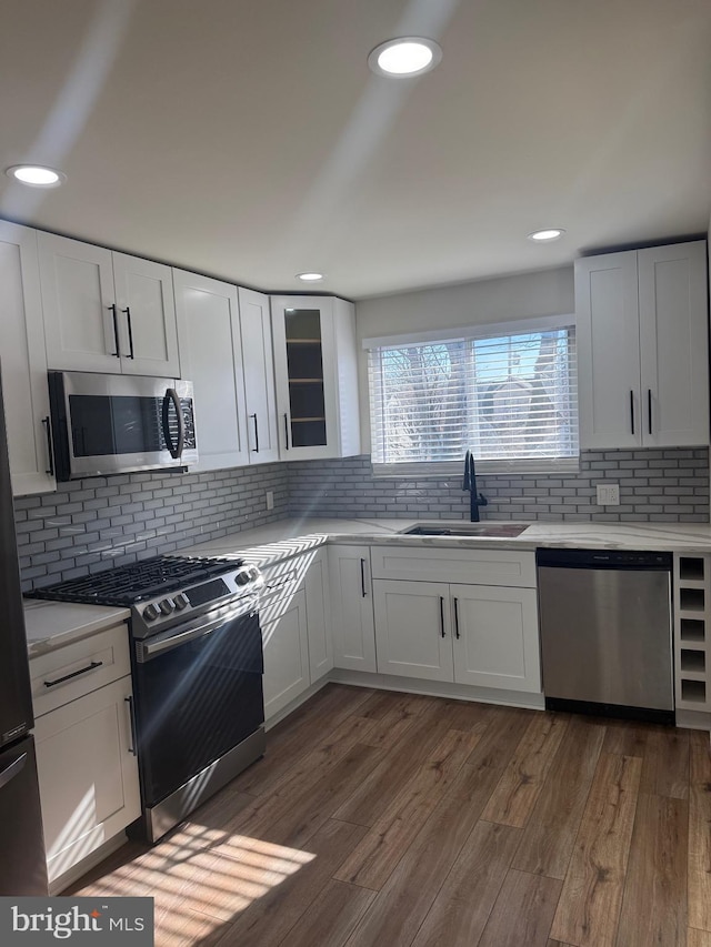 kitchen featuring appliances with stainless steel finishes, tasteful backsplash, white cabinetry, sink, and dark wood-type flooring