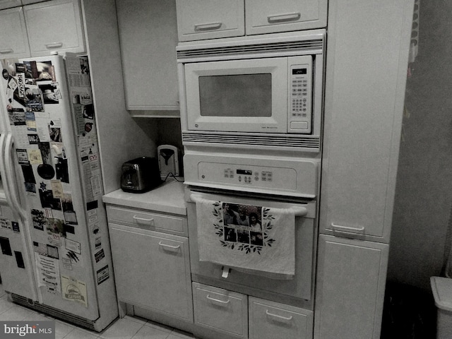 kitchen with light tile patterned floors, light countertops, and white appliances