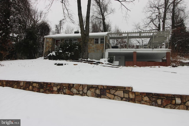 view of front of home featuring stone siding and a pergola