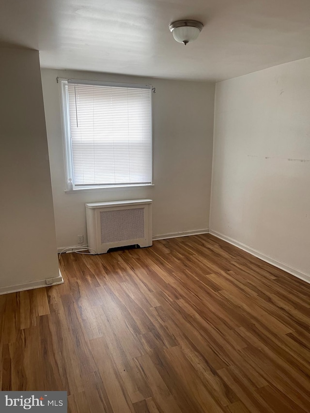 unfurnished room featuring radiator and dark hardwood / wood-style flooring