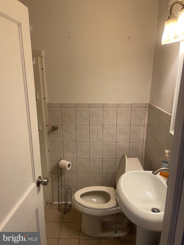 bathroom featuring sink, toilet, tile patterned flooring, and tile walls