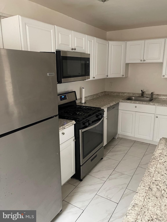 kitchen with stainless steel appliances, white cabinetry, and sink