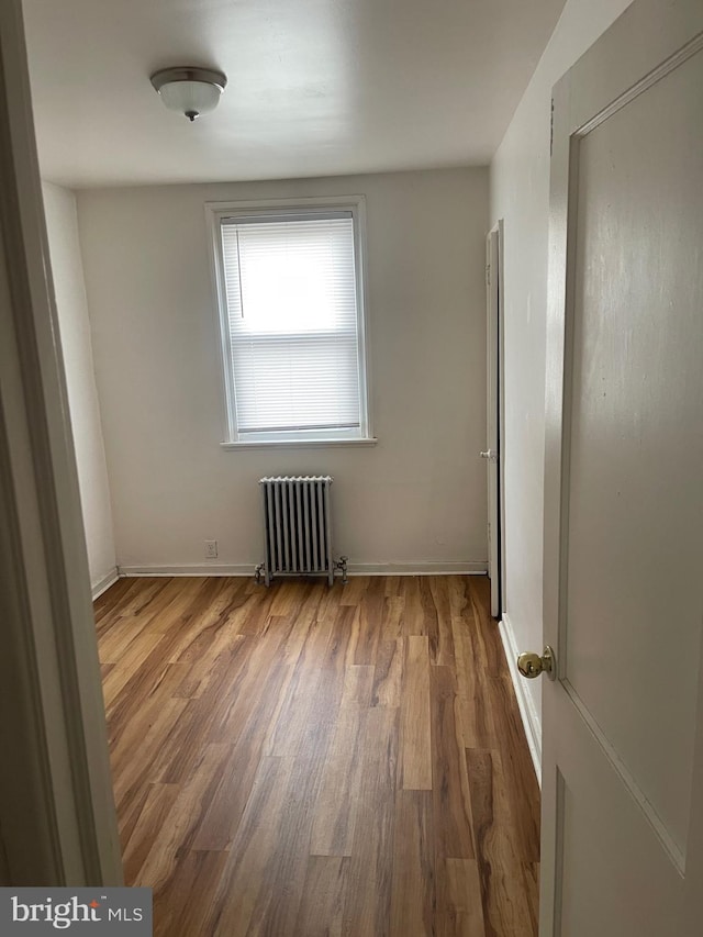 empty room with wood-type flooring and radiator