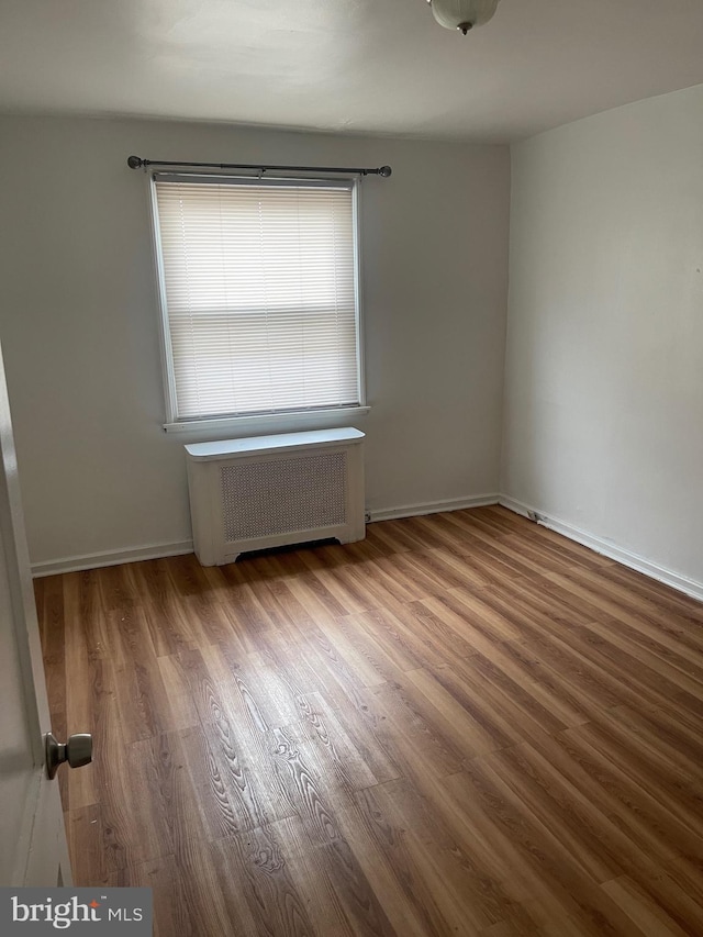 unfurnished room featuring radiator and hardwood / wood-style flooring