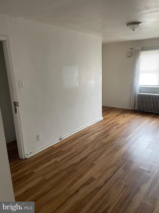 empty room featuring radiator heating unit and dark hardwood / wood-style floors