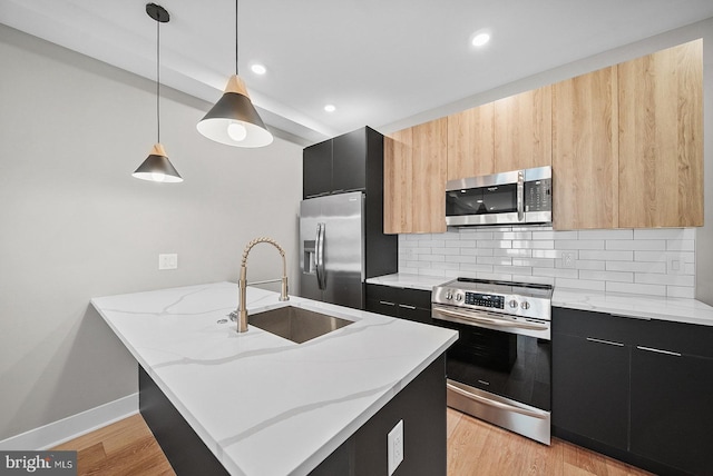 kitchen with tasteful backsplash, sink, hanging light fixtures, stainless steel appliances, and light stone countertops