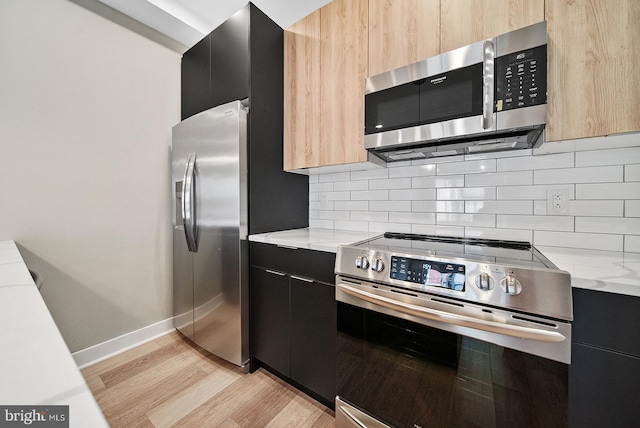 kitchen featuring light stone counters, light hardwood / wood-style flooring, light brown cabinets, stainless steel appliances, and backsplash