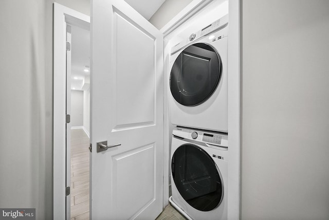 laundry room with stacked washing maching and dryer and light hardwood / wood-style flooring