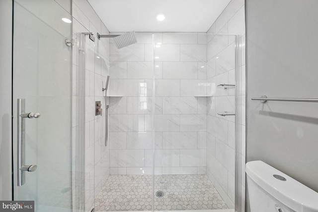 bathroom featuring a shower with door and toilet